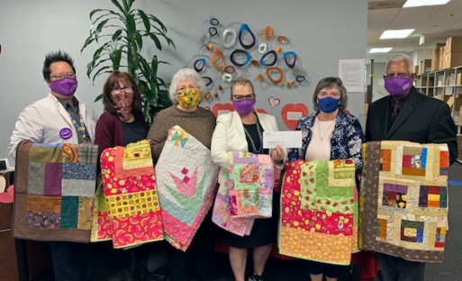 Six Guild members hold up quilts they have created